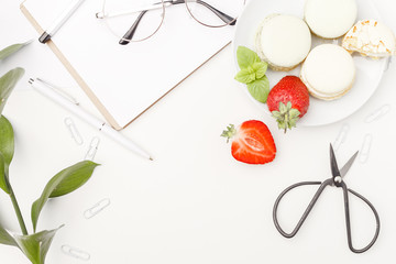 Flowers, notepad, glasses, scissors, cakes and strawberry on a white table. Flatlay. Top view. For design.
