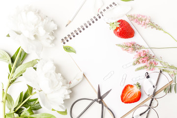 Flowers, notepad, glasses, scissors and strawberry on a white table. Flatlay. Top view. For design.