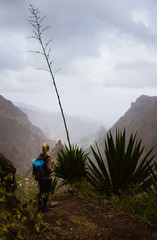 Obraz premium Female hiker in dusty mountain terrain enjoy spectacular view of sharp summits in the fog. Santo Antao Island Cape Verde