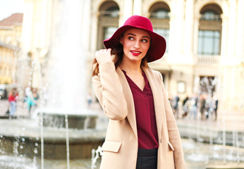 Obraz premium Cute smiling woman in coat and on street tourist town