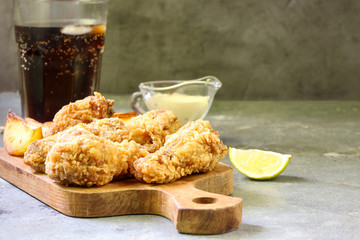 Fried chicken wings on concrete table. Breaded Crispy fried chicken wings with French fries with cheese sauce and soda