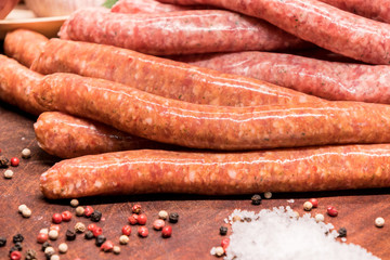 raw sausages with chilli and herbs on a wooden board with spices
