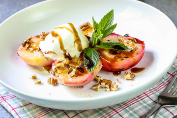 Baked peaches with ice cream on a plate on a gray metal background