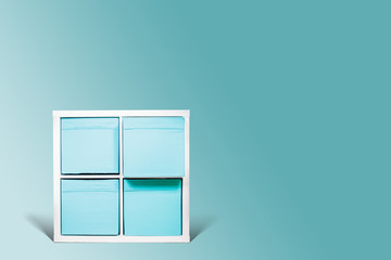 White dresser with blue drawers and shelves on a pastel blue background. Isolated bookcase on a...