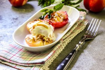 Baked peaches with ice cream on a plate on a gray metal background