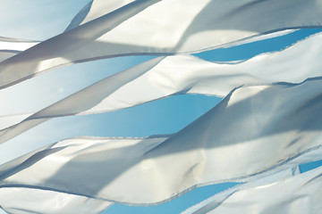 A waving white long triungular flags and ribbons closeup on a background bright blu sky