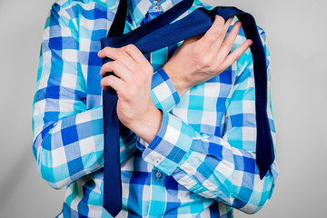 Putting on and tying a tie. The man is holding a tie. Instructions for putting on a tie. Preparation for the windsor node. Front view of a man in a blue shirt.