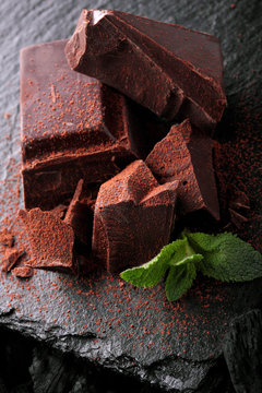 Dark chocolate stack, and powder.Closeup.With leaf of mint hocolate.Sweet delicious.On dark background