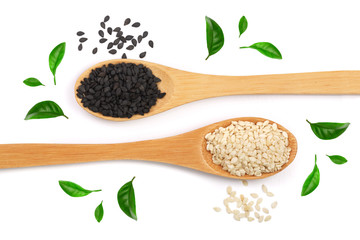 Black and white sesame seeds in a wooden spoon isolated on white background decorated with green leaves. op view