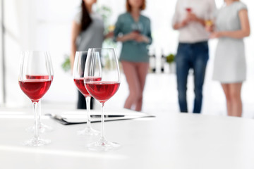 Glasses with delicious wine and blurred people on background