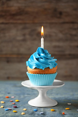 Delicious birthday cupcake with candle on table
