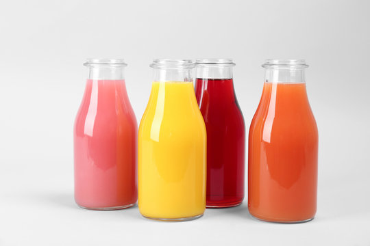 Bottles with delicious colorful juices on light background