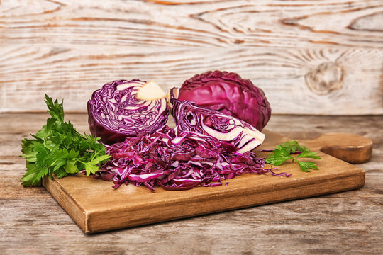 Wooden board with chopped purple cabbage and parsley on table