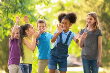 Cute little children playing with soap bubbles outdoors on sunny day
