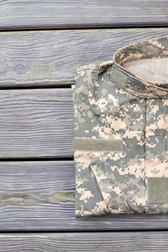 Neatly Folded Military Jacket. Wooden Desk Table Background.