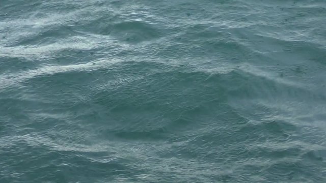 Rain drops fall on the sea surface.