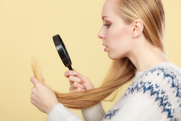 Sad woman looking at damaged hair ends.