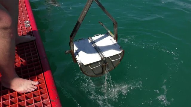 Marine Research: The sampler for sampling bottom animals (bottom grabber) rises on the deck of a scientific vessel.