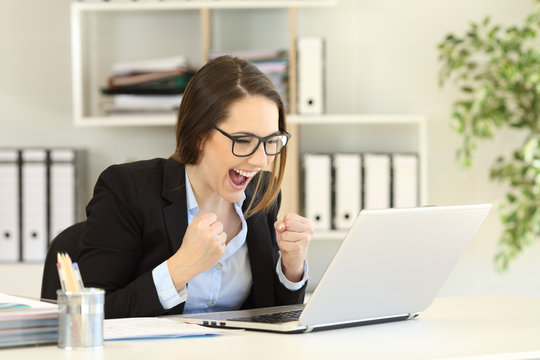 Excited office worker reading online news in a laptop