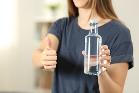 Woman hands holding a bottle of water with thumbs up