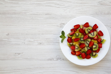 Fresh fruit salad on white wooden background, top view.