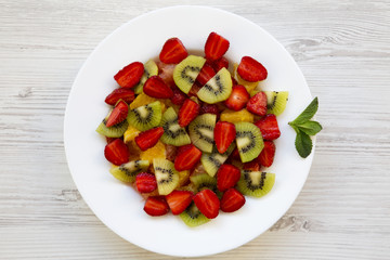 Fresh fruit salad on white wooden background, top view. Flat lay. From above.
