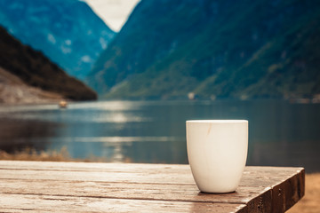 Mug on wooden table, fjord norwegian landscape