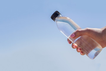 bottle with water in hand on the background of the sea