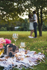 Summertime picnic setting on the grass with fruit, flowers, croissants and glass of wine