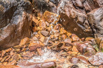 Small waterfall among rocks and stones in moss