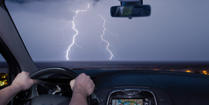 Driving a car towards a lightning storm over the sea