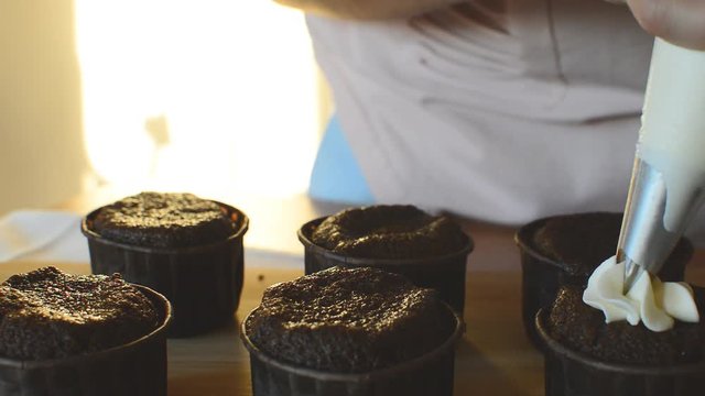 girl puts a delicious white cream on mafin