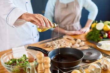 Foto op Plexiglas Koken Close-up van mannelijke chef-kok die olie in de pan giet