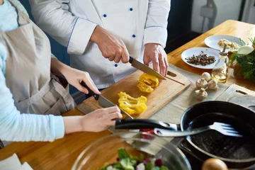 Photo sur Plexiglas Cuisinier Gros plan du chef et de son assistant préparant la salade ensemble