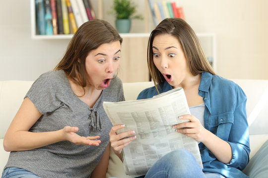 Amazed friends reading newspaper news