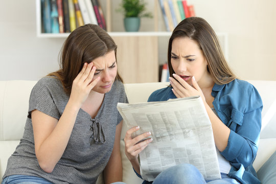 Worried friends reading newspaper news