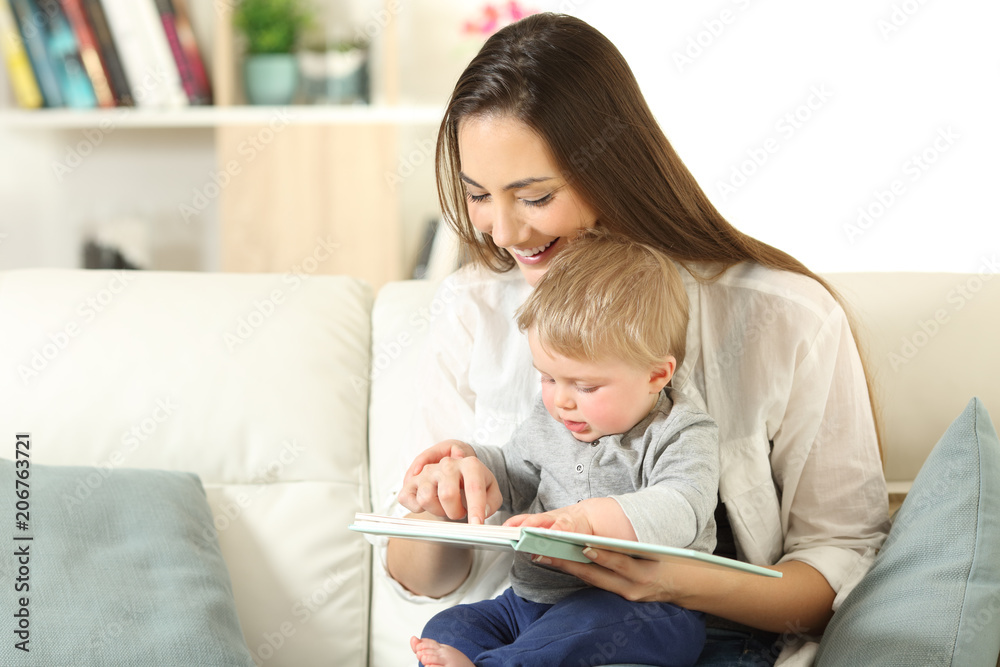 Wall mural Baby and mother reading a book together