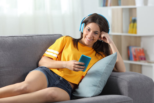 Teen listening to music looking at camera at home