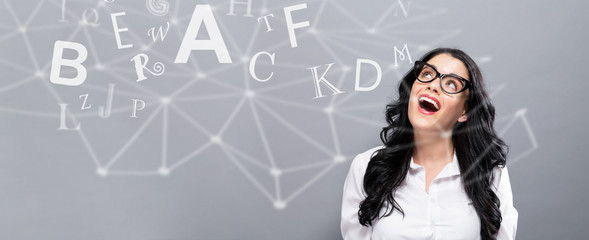 Alphabets with happy young businesswoman on a gray background