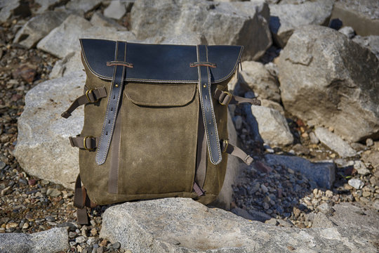 Vintage kraft cloth backpack with leather top stands on stones. HDR image