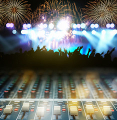 Closeup up hands the sound mixer over the photo blurred of Concert crowd in silhouettes of Music fanclub follow up the songer at the front of stage with multicolors fireworks follow light