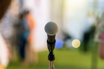 Microphone on the stage over the Abstract blurred photo of green grass with bokeh of light background, Musical and presentation concept