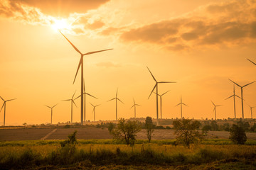 Fototapeta na wymiar Wind turbines generating electricity on mountain in sunset evening
