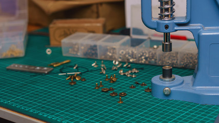 Tools of the tanner. Riveter, awl rivets and fasteners are on the table. Close-up photo, side view.