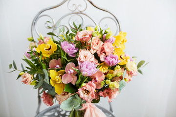 Spring bouquet of flowers with orchids, tulips and eustoma. Pink yellow flower arrangement