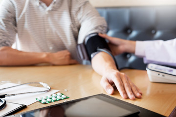 Fototapeta premium healthcare, hospital and medicine concept - doctor and patient measuring blood pressure by machine