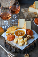 Rose wine and a variety of cheese on a wooden table