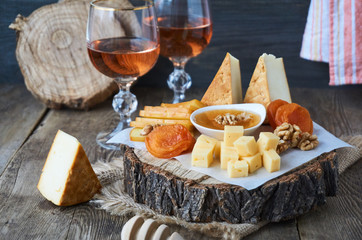 Rose wine and a variety of cheese on a wooden table