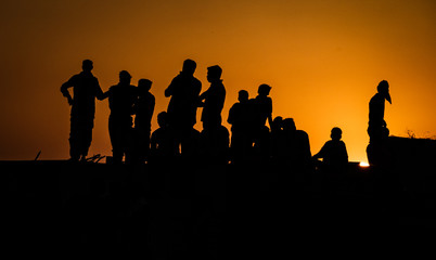 Fototapeta premium Silhouette of people standing on roof watching festivities below at sunset