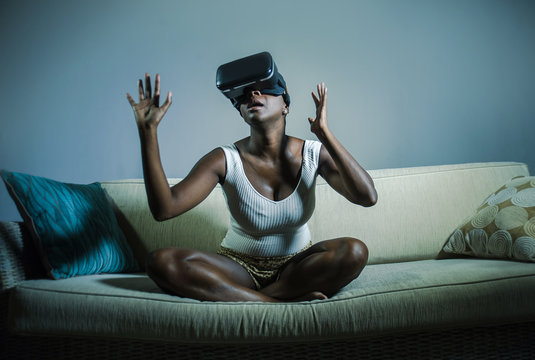 Fototapeta young attractive black afro American woman playing amazed and surprised virtual reality video game wearing VR goggles headset trying to touch illusion